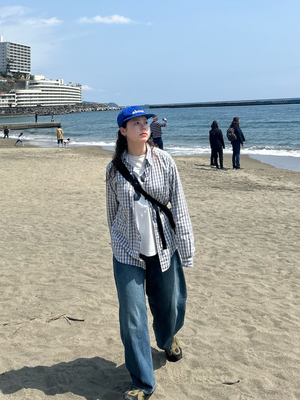 ブルー系のデニムパンツ、グリーン系のスニーカー、ブラック系のショルダーバッグを着用したレディースの春コーディネートの2枚目の写真