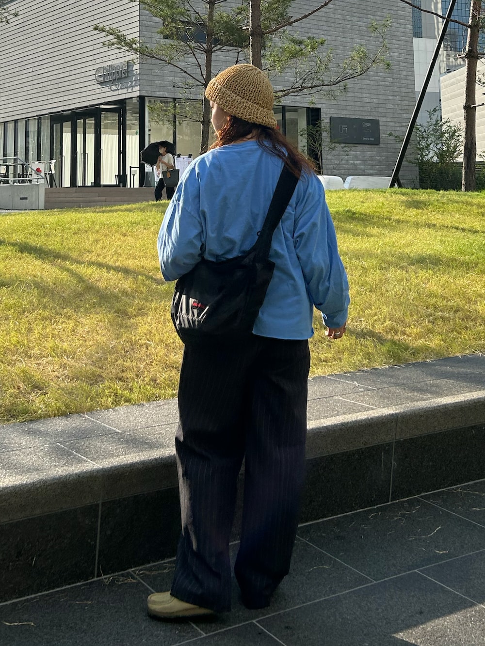 ブルー系のスラックス、ベージュ系のモカシン/デッキシューズ、ブラック系のショルダーバッグを着用したレディースの秋コーディネートの2枚目の写真