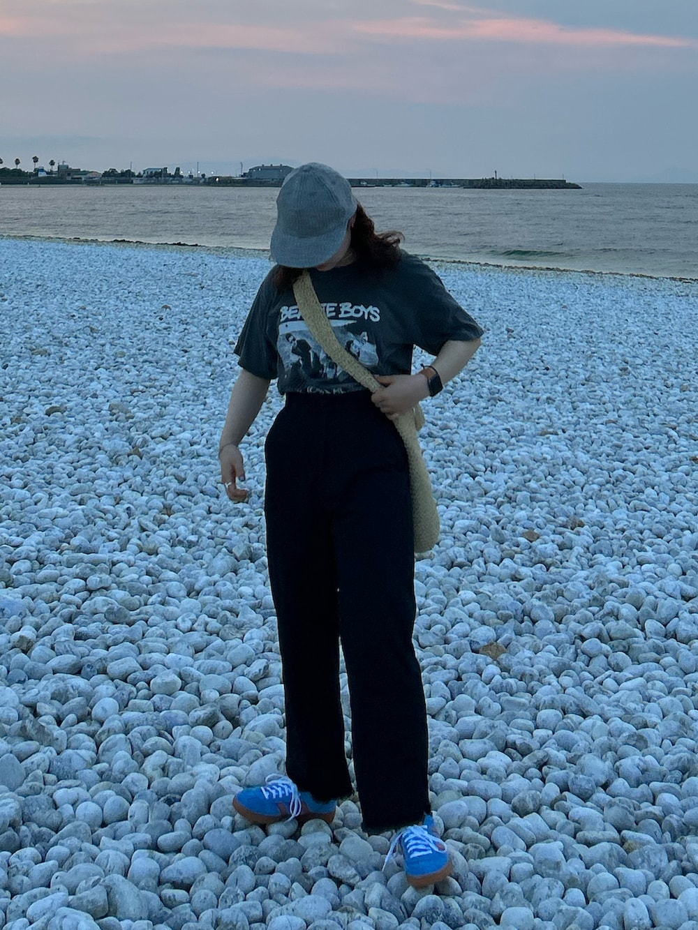 ベージュ系のショルダーバッグ、ブラック系のチノパンツ、ブルー系のスニーカーを着用したレディースの夏コーディネートの3枚目の写真