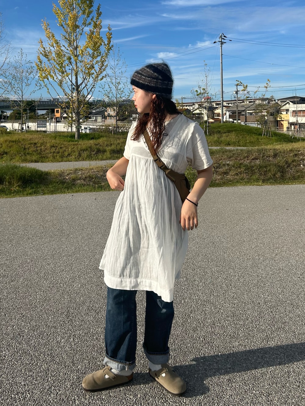 ブラック系のショルダーバッグ、ホワイト系のチュニック、ベージュ系のTシャツ/カットソーを着用したレディースの秋コーディネートの2枚目の写真