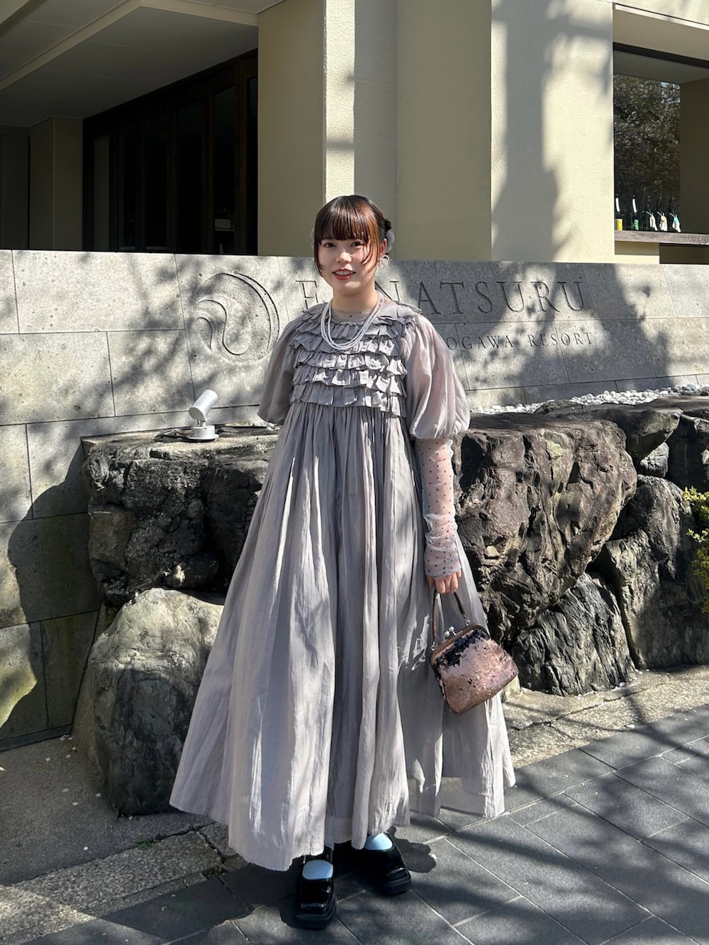グレー系のワンピース、ブラック系のパンプス、グレー系のTシャツ/カットソーを着用したレディースの夏コーディネートの2枚目の写真
