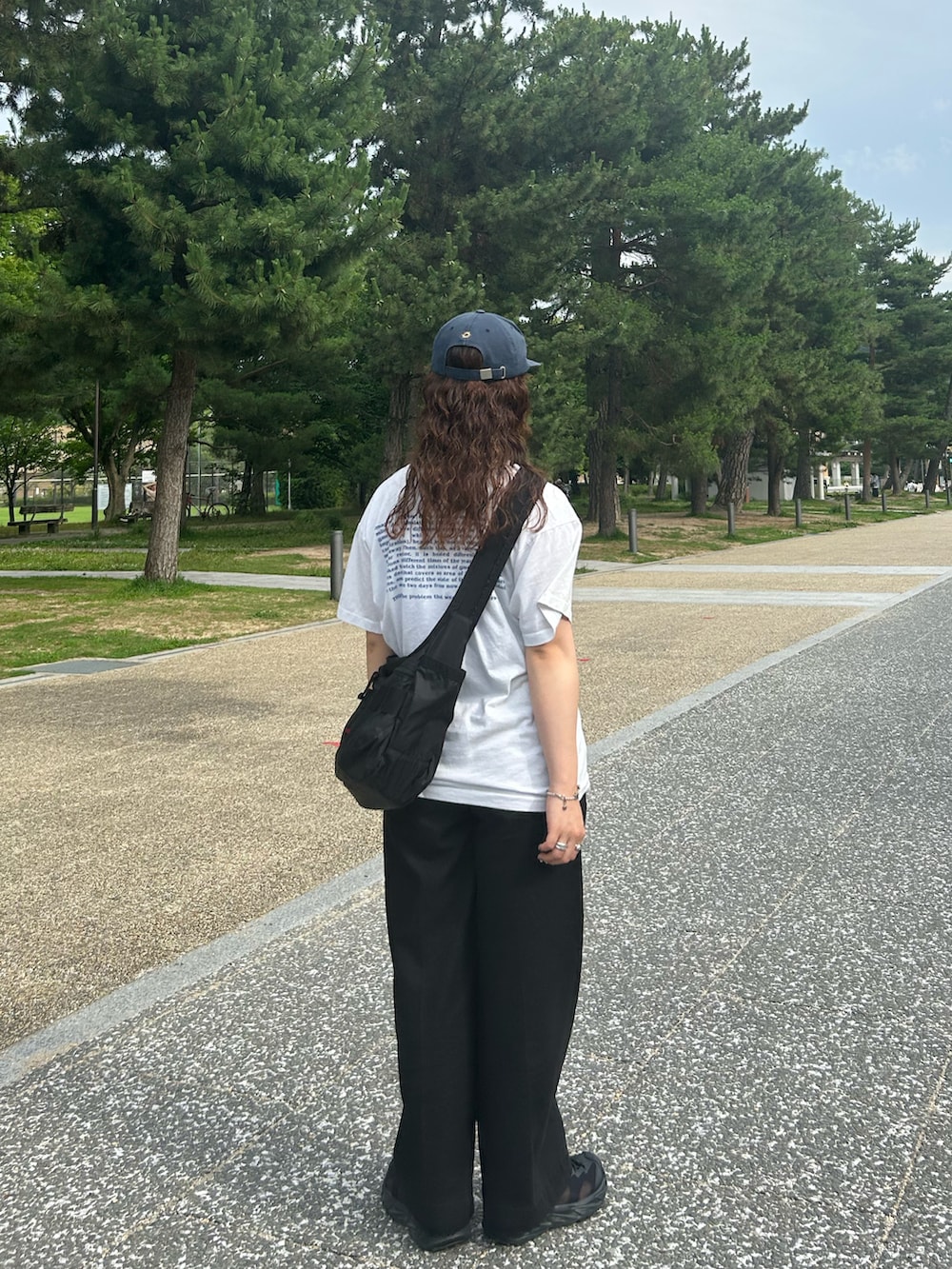ブラック系のサンダル、ブラック系のスラックス、ホワイト系のTシャツ/カットソーを着用したレディースの夏コーディネートの3枚目の写真