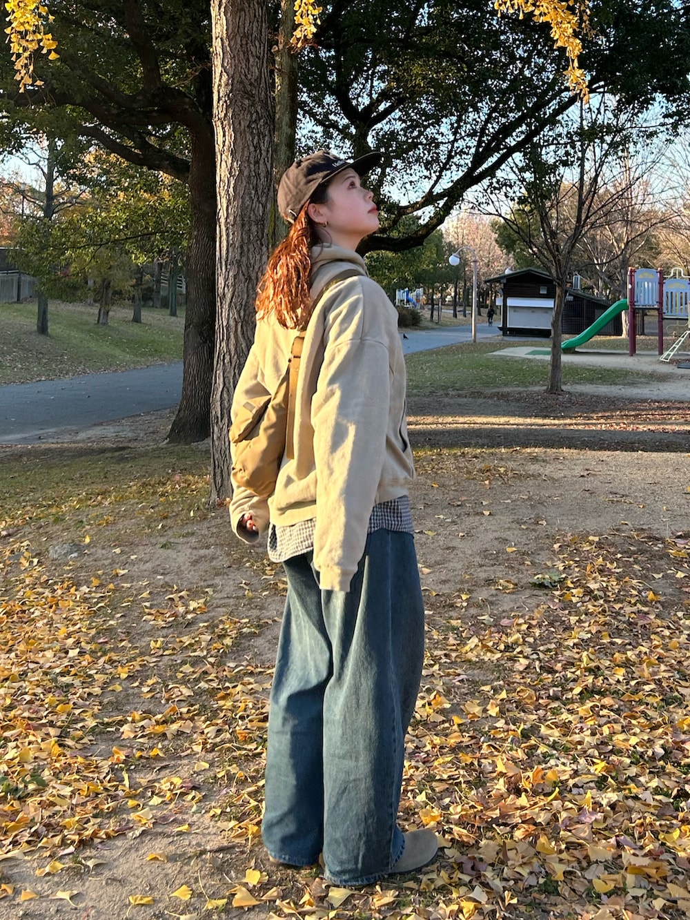 ブルー系のデニムパンツ、ベージュ系のパーカー、ブラック系のショルダーバッグを着用したレディースの冬コーディネートの3枚目の写真