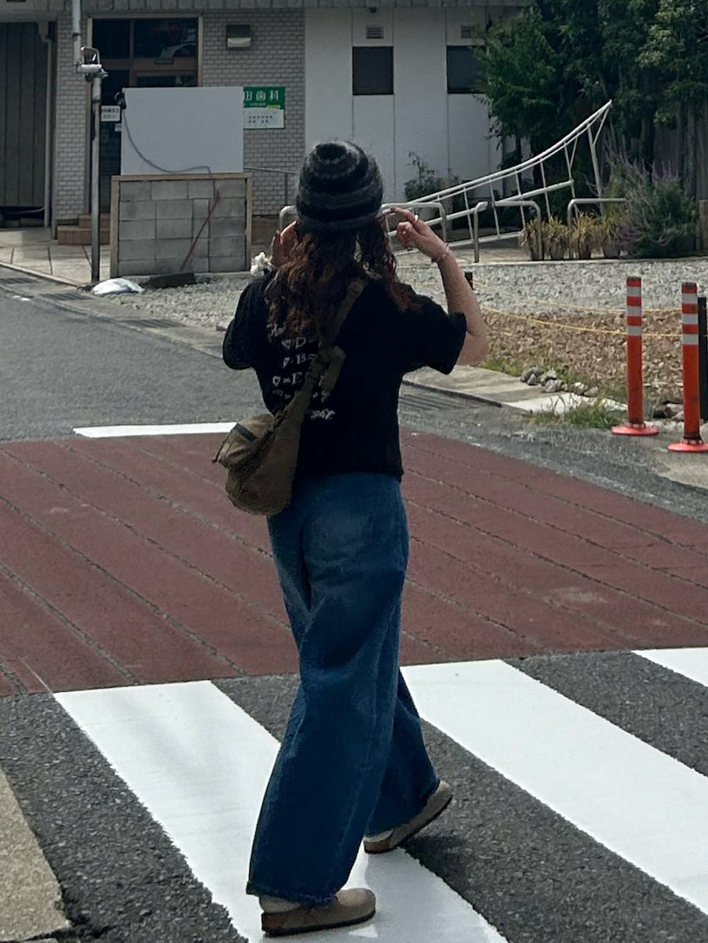 ブラック系のTシャツ/カットソー、ブラック系のショルダーバッグ、ブルー系のデニムパンツを着用したレディースの秋コーディネートの2枚目の写真