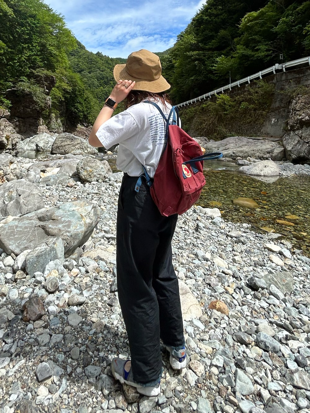 ブラック系のチノパンツ、シルバー系のスニーカー、レッド系のバックパック/リュックを着用したレディースの夏コーディネートの3枚目の写真