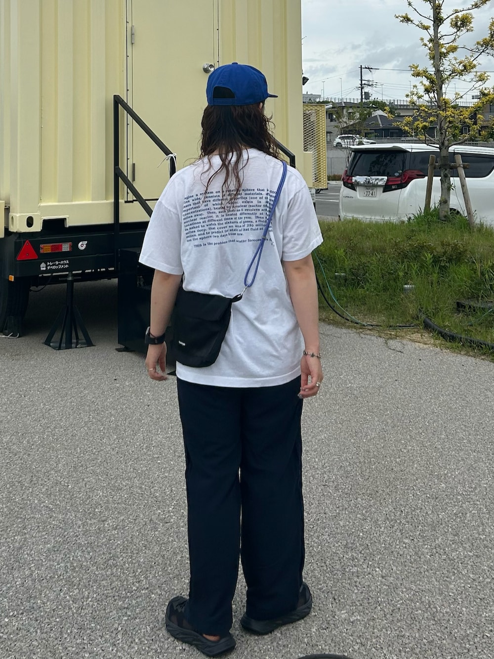 ブルー系のパンツ、ブラック系のサンダル、ホワイト系のTシャツ/カットソーを着用したレディースの夏コーディネートの2枚目の写真