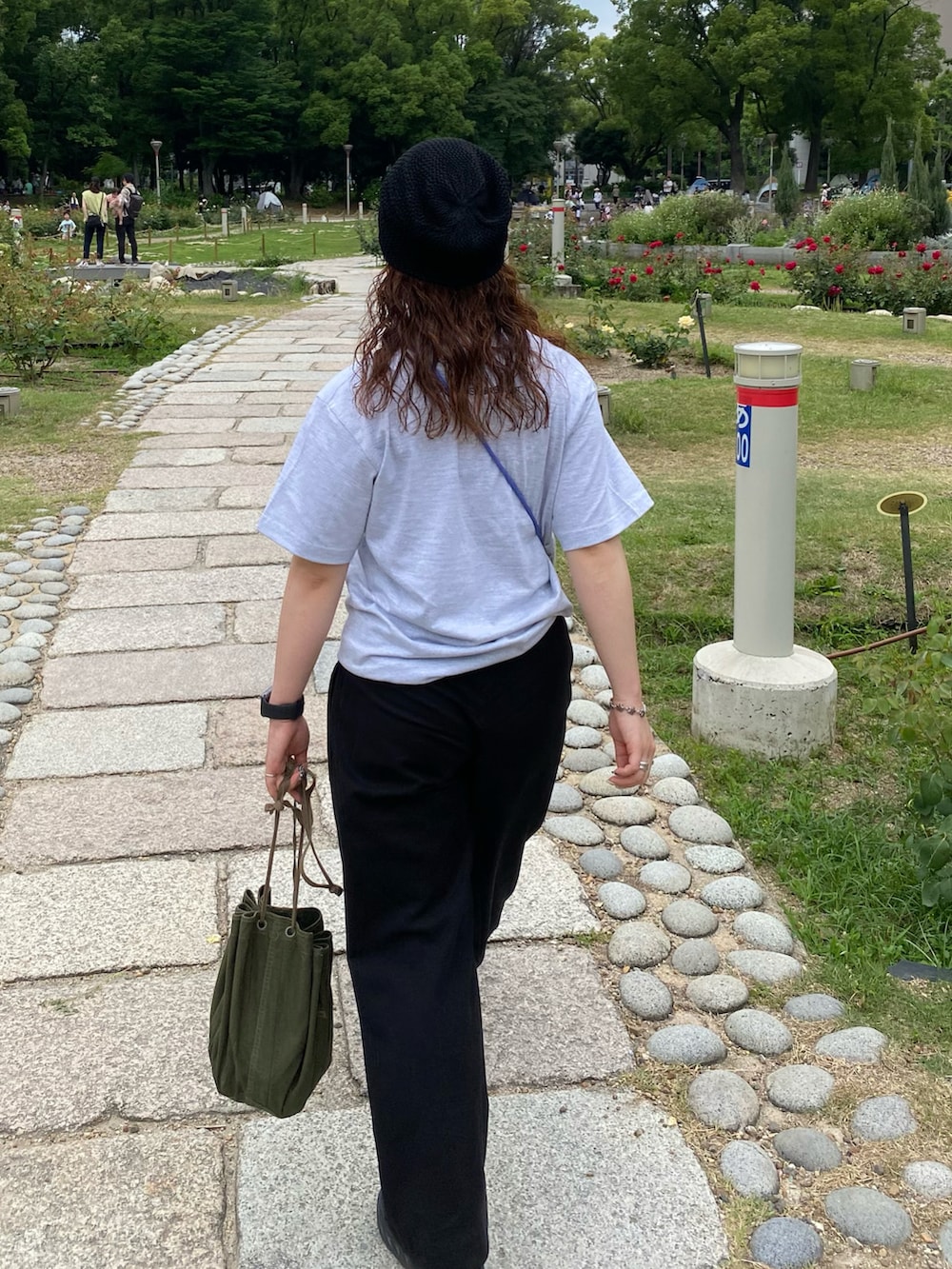 グレー系のTシャツ/カットソー、グリーン系のハンドバッグ、ブラック系のスラックスを着用したレディースの夏コーディネートの3枚目の写真