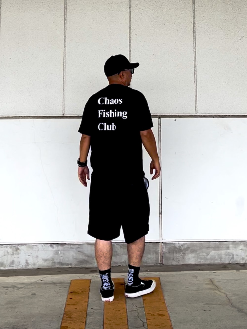 ブラック系のTシャツ/カットソー、ブラック系のチノパンツ、ブラック系のスニーカーを着用したメンズの夏コーディネートの2枚目の写真