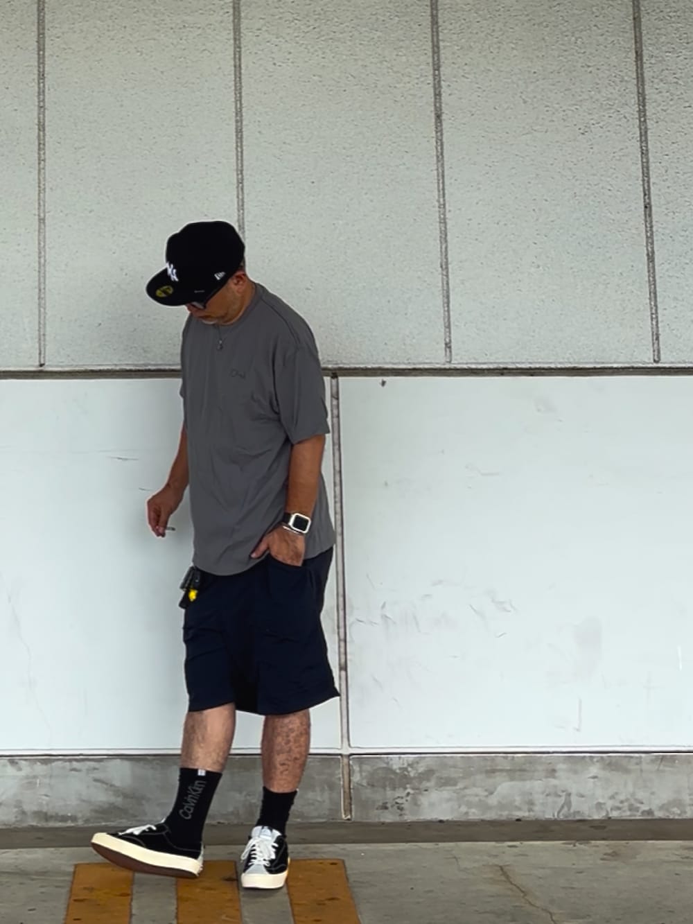 グレー系のTシャツ/カットソー、ブラック系のスニーカー、ブルー系のキャップを着用したメンズの夏コーディネートの2枚目の写真