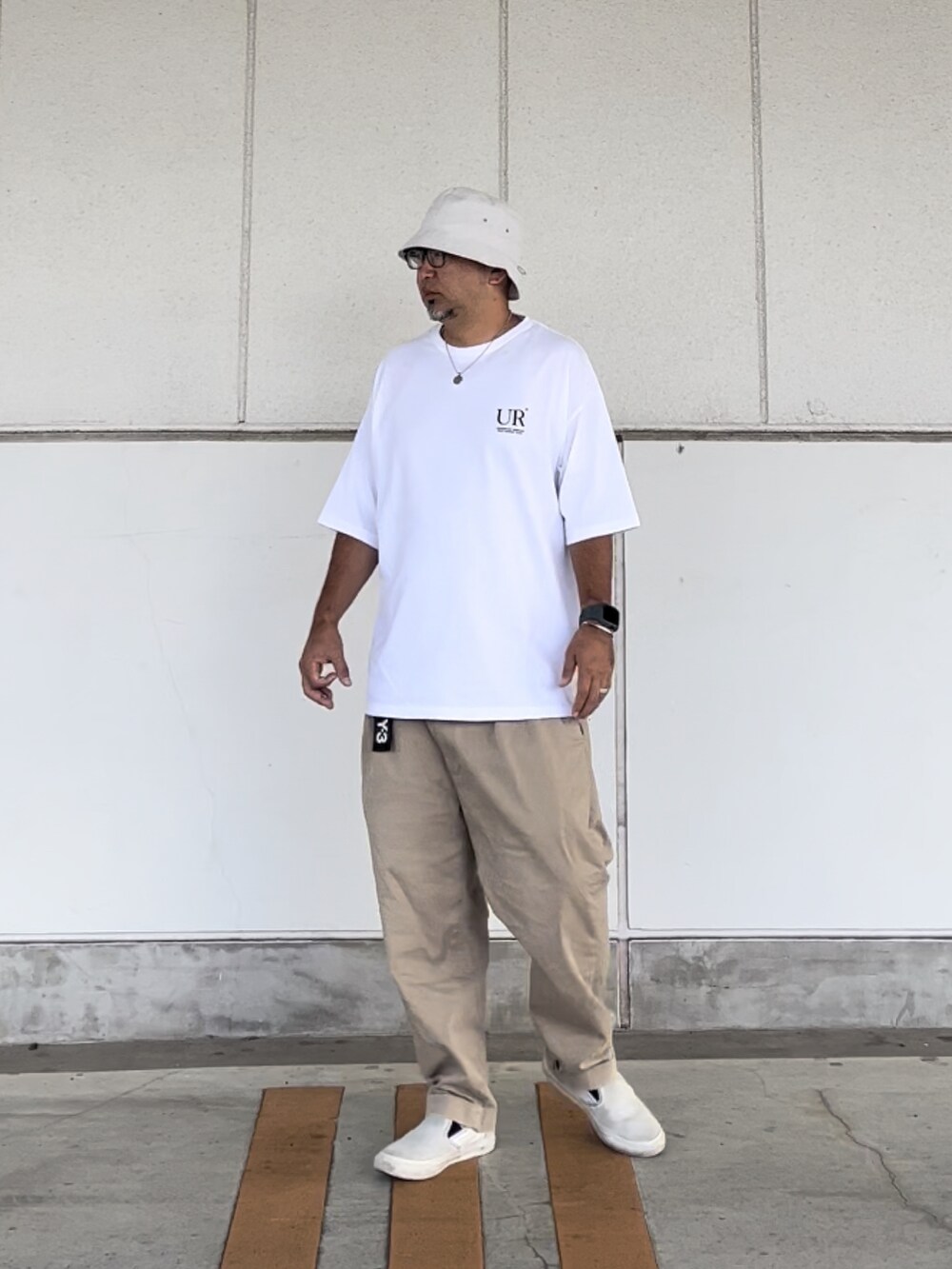 ホワイト系のTシャツ/カットソー、ベージュ系のチノパンツ、ホワイト系のスニーカーを着用したメンズの夏コーディネートの2枚目の写真