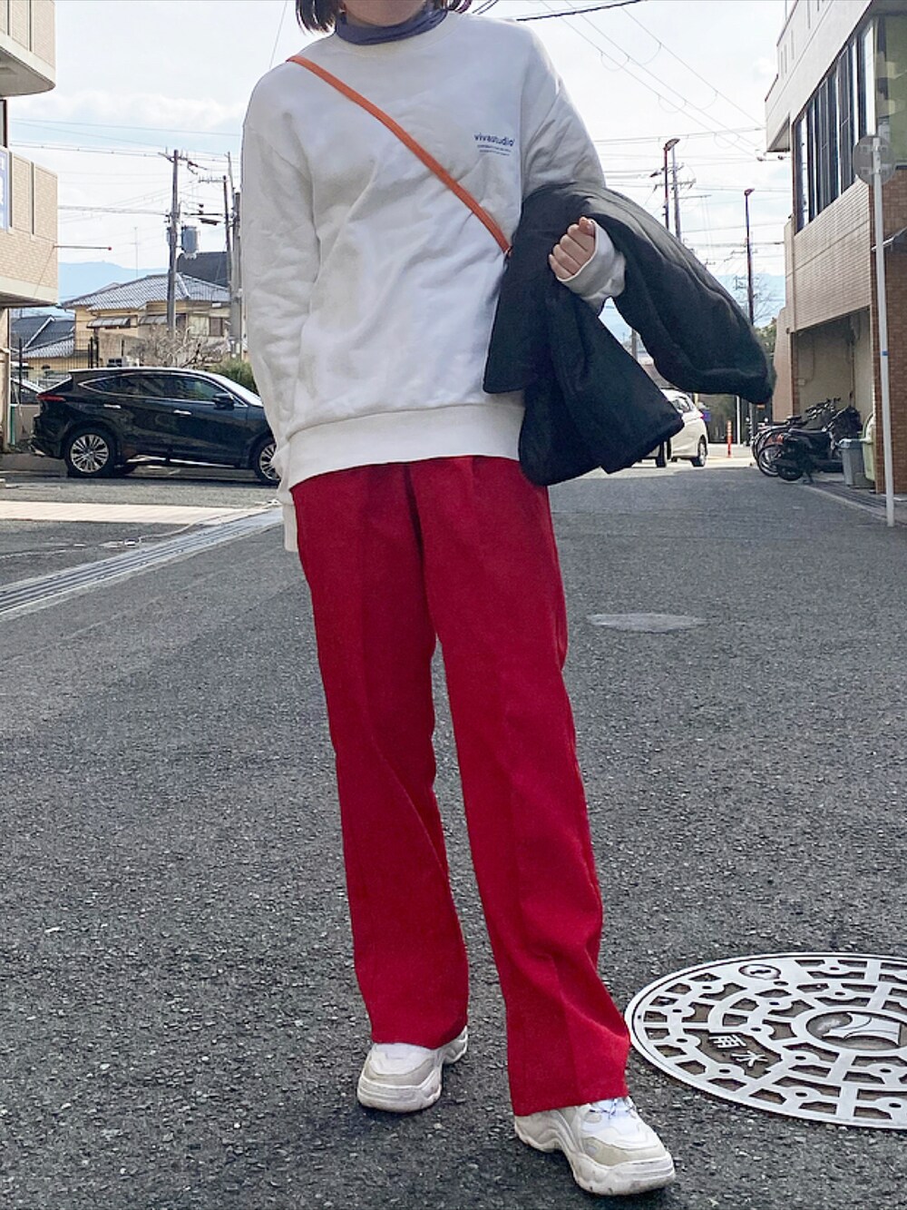 レッド系のスラックス、ホワイト系のスニーカー、ベージュ系のスウェットを着用したレディースの冬コーディネートの2枚目の写真