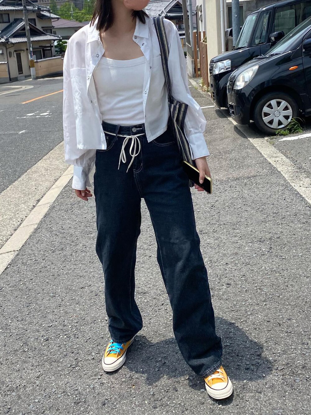 ブルー系のデニムパンツ、オレンジ系のスニーカー、ブルー系のトートバッグを着用したレディースの夏コーディネートの2枚目の写真