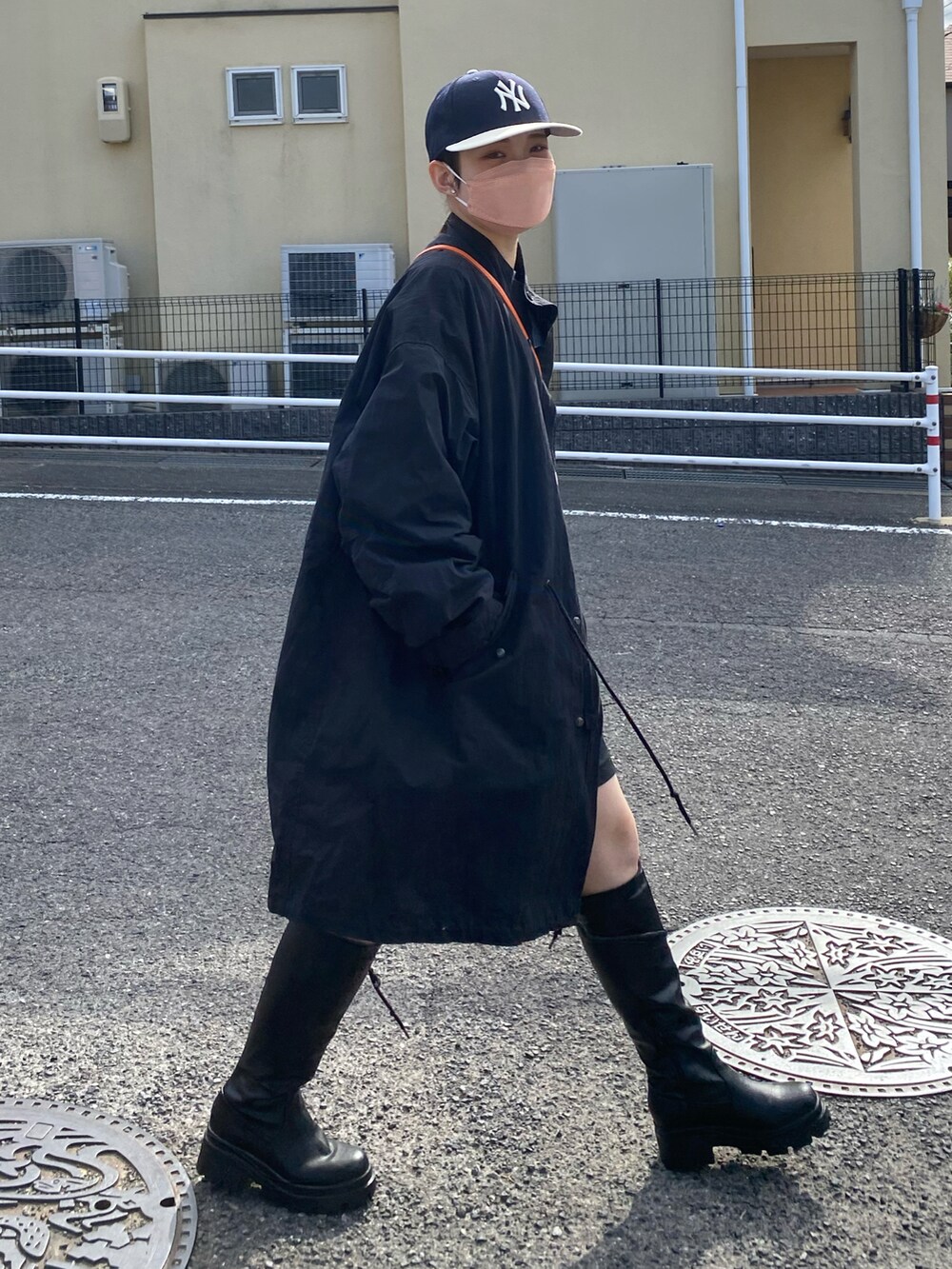 オレンジ系のハンドバッグ、ブラック系のモッズコート、ブラック系のブーツを着用したレディースの冬コーディネートの3枚目の写真