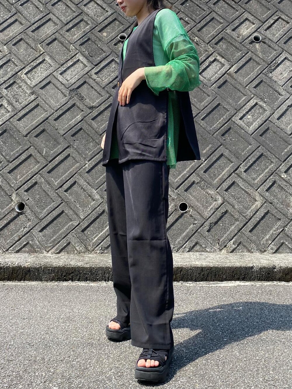 ブラック系のスラックス、ブラック系のサンダル、ブラック系のベストを着用したレディースの夏コーディネートの3枚目の写真