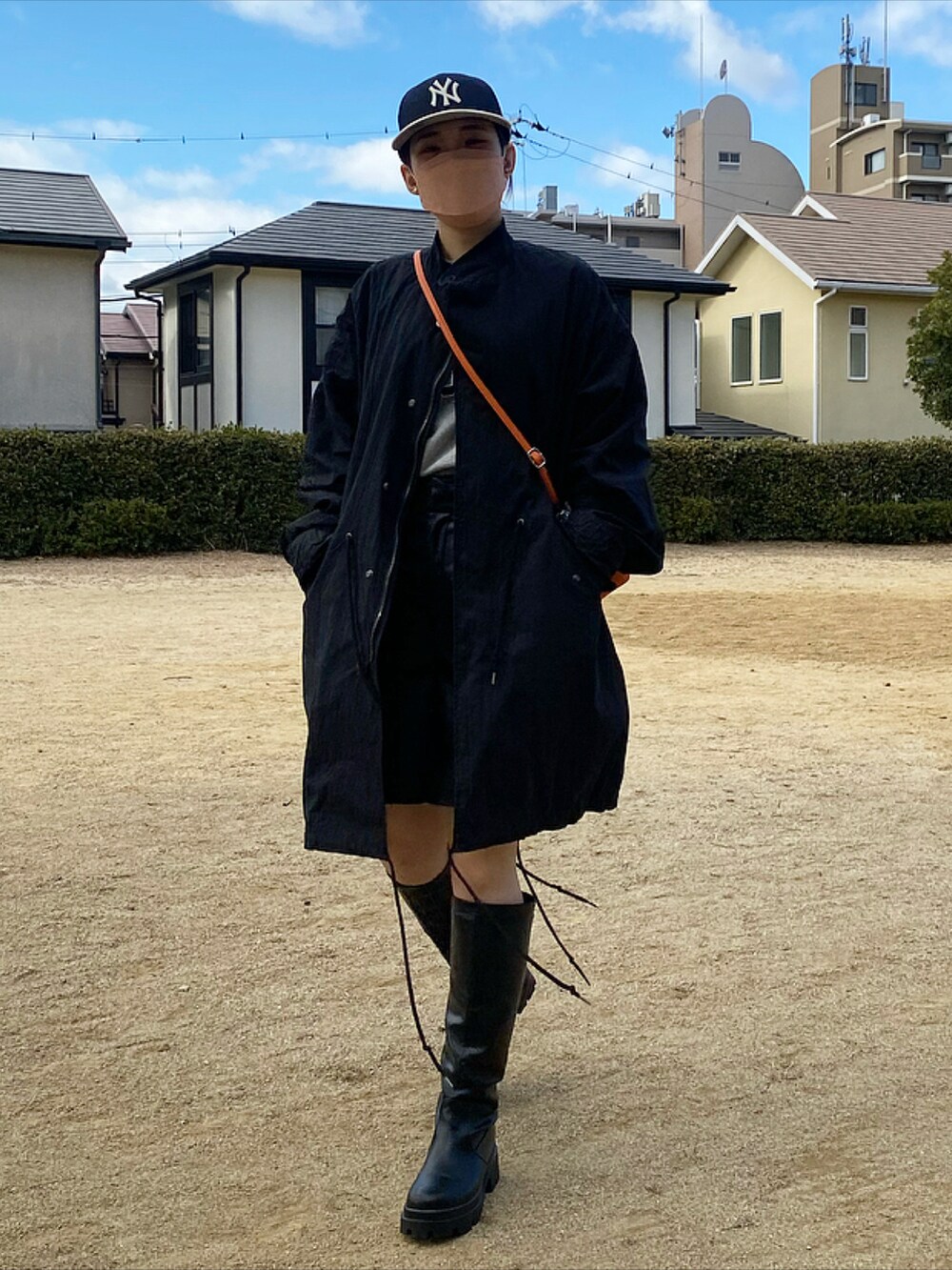 オレンジ系のハンドバッグ、ブラック系のモッズコート、ブラック系のブーツを着用したレディースの冬コーディネートの2枚目の写真