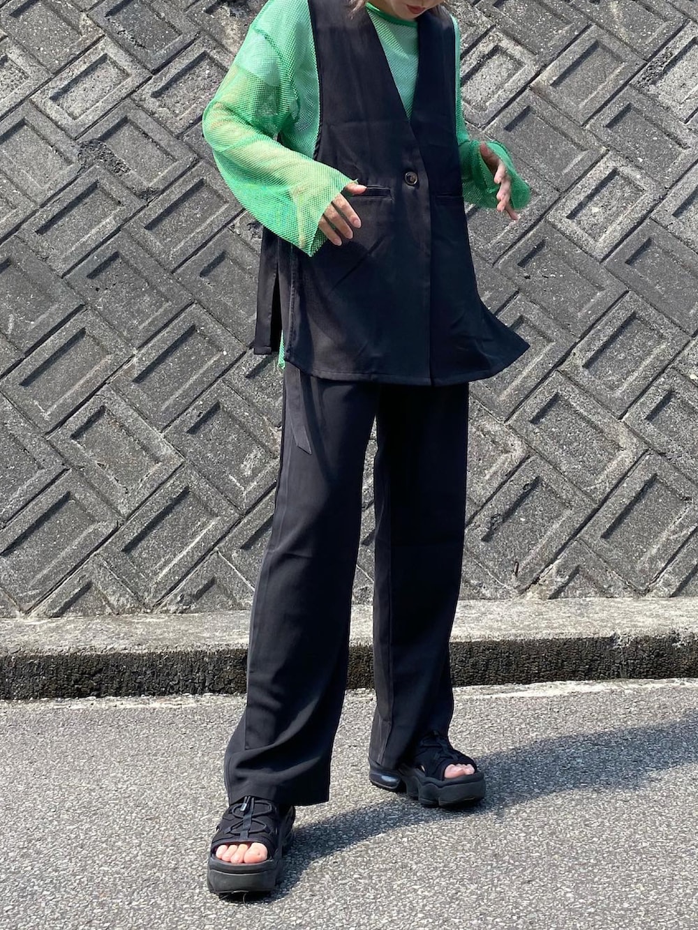 ブラック系のスラックス、ブラック系のサンダル、ブラック系のベストを着用したレディースの夏コーディネートの2枚目の写真