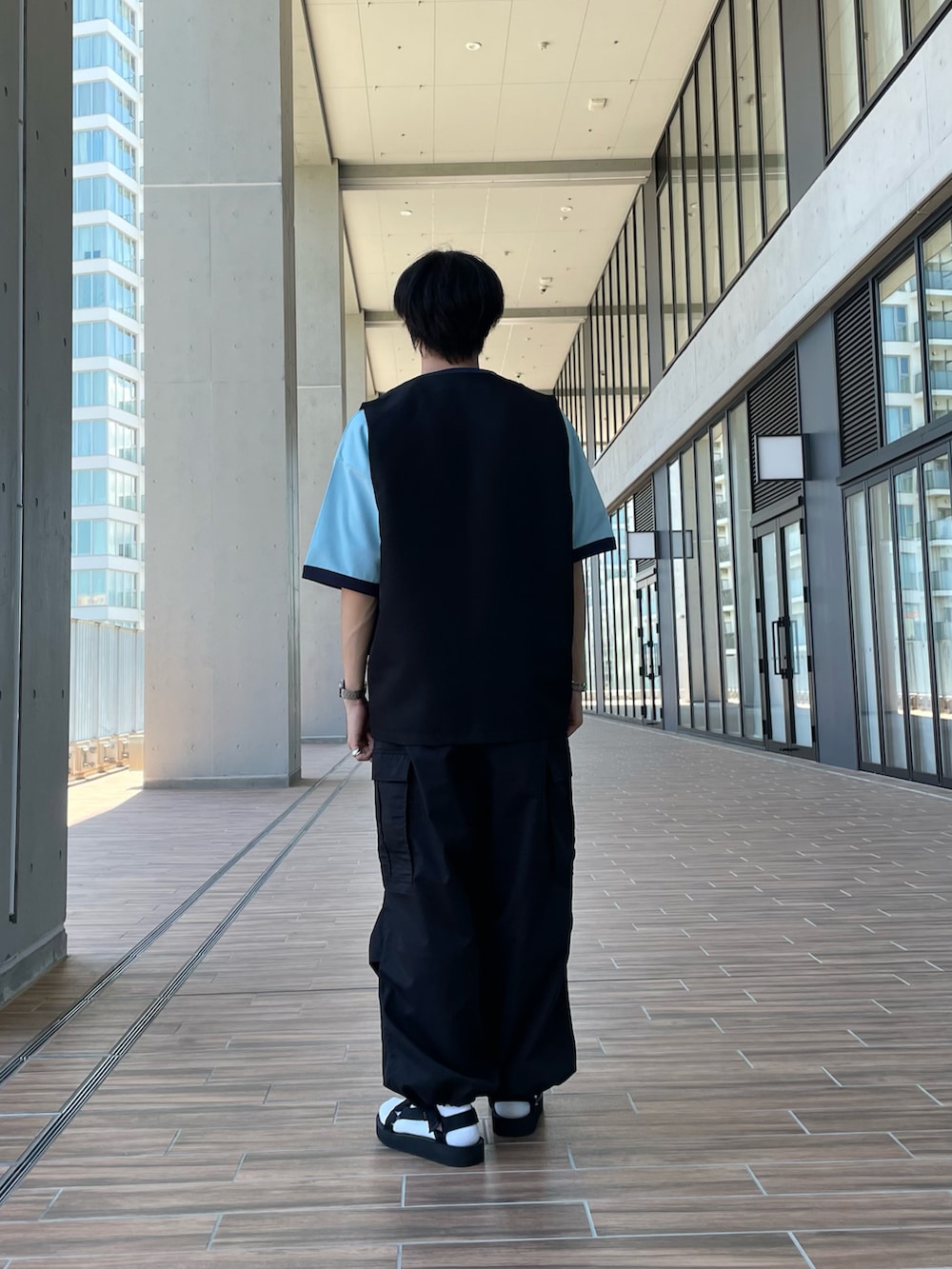 ブルー系のTシャツ/カットソー、ブラック系のベスト、ブラック系のサンダルを着用したメンズの夏コーディネートの2枚目の写真