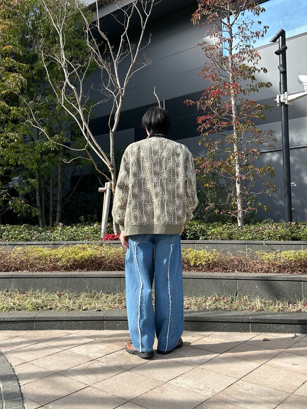 グリーン系のスタジャン、ベージュ系のポロシャツ、ブルー系のデニムパンツを着用したメンズの冬コーディネートの2枚目の写真