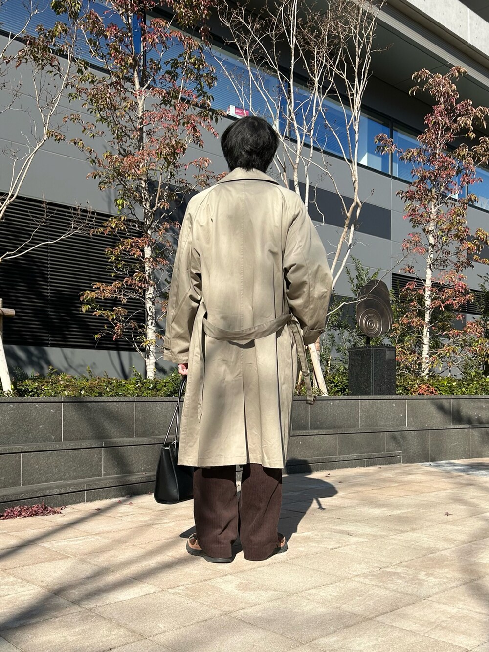 グリーン系のニット/セーター、ベージュ系のトレンチコート、ブラウン系のその他パンツを着用したメンズの冬コーディネートの2枚目の写真