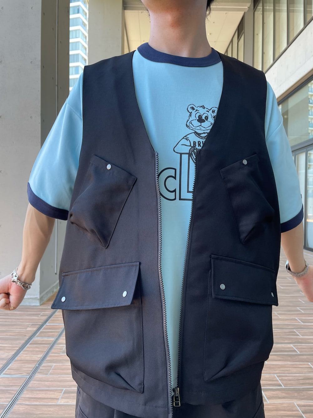ブルー系のTシャツ/カットソー、ブラック系のベスト、ブラック系のサンダルを着用したメンズの夏コーディネートの3枚目の写真