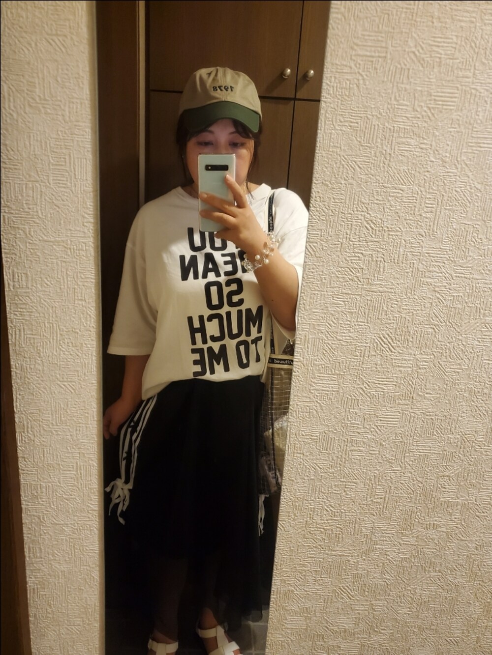 ホワイト系のTシャツ/カットソー、ブラック系のスカート、ホワイト系のサンダルを着用したレディースの夏コーディネートの2枚目の写真