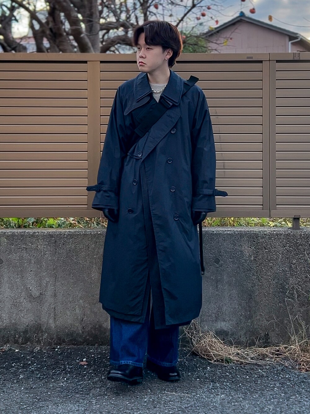 ブラック系のトレンチコート、グレー系のニット/セーター、ブルー系のデニムパンツを着用したメンズの冬コーディネートの5枚目の写真