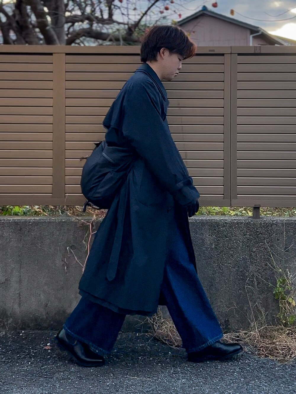 ブラック系のトレンチコート、グレー系のニット/セーター、ブルー系のデニムパンツを着用したメンズの冬コーディネートの4枚目の写真