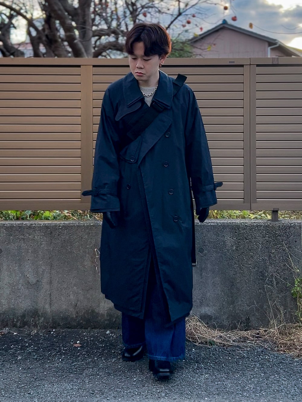 ブラック系のトレンチコート、グレー系のニット/セーター、ブルー系のデニムパンツを着用したメンズの冬コーディネートの3枚目の写真