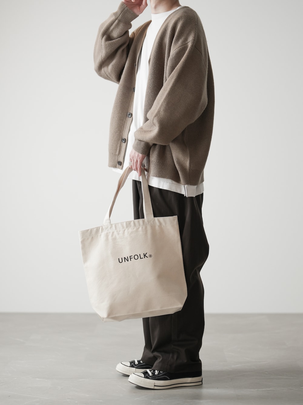 ブラウン系のカーディガン/ボレロ、ホワイト系のTシャツ/カットソー、ブラウン系のスラックスを着用したメンズの春コーディネートの2枚目の写真