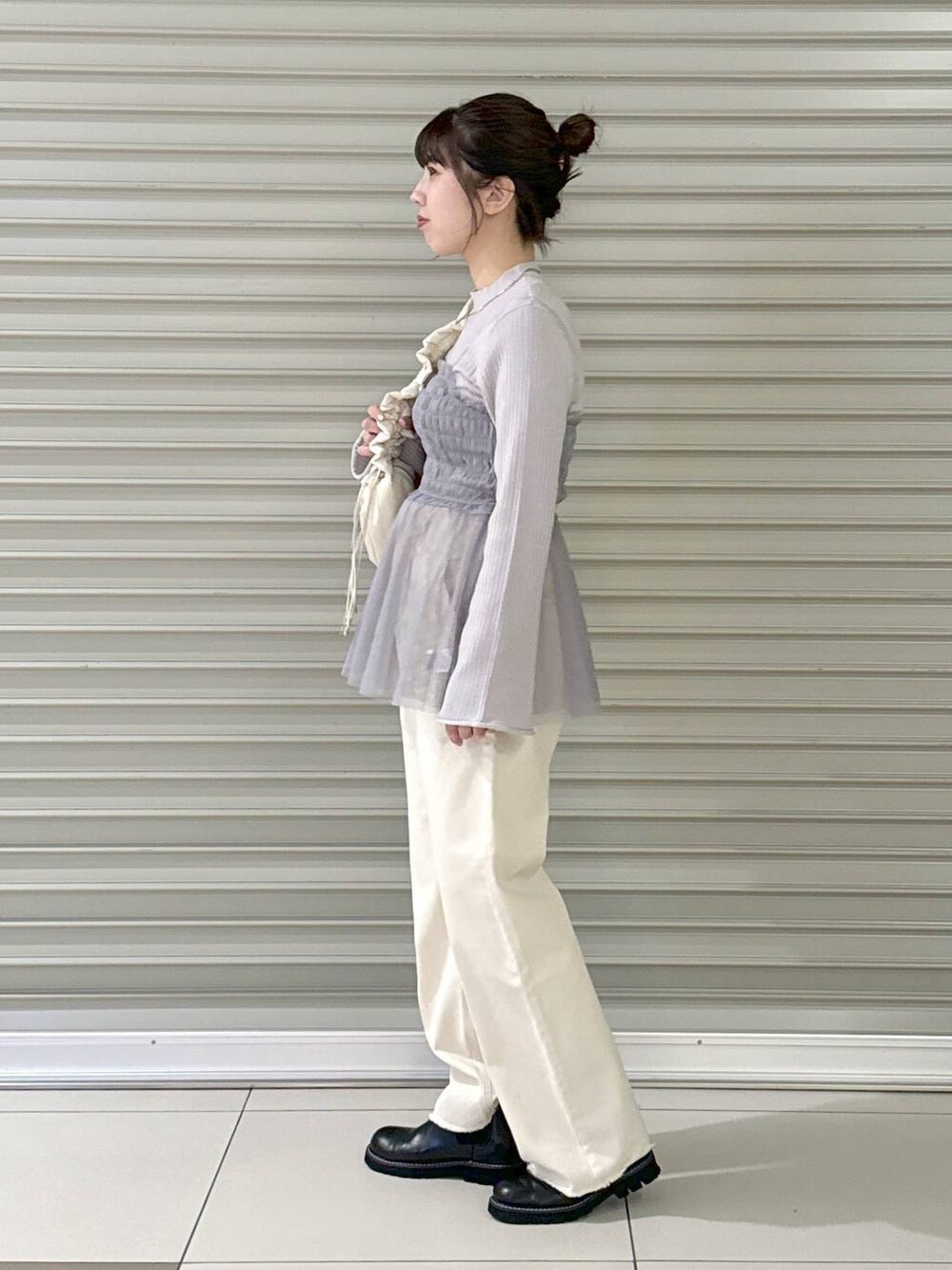 ホワイト系のデニムパンツ、ホワイト系のハンドバッグ、ブラック系のブーツを着用したレディースの冬コーディネートの3枚目の写真