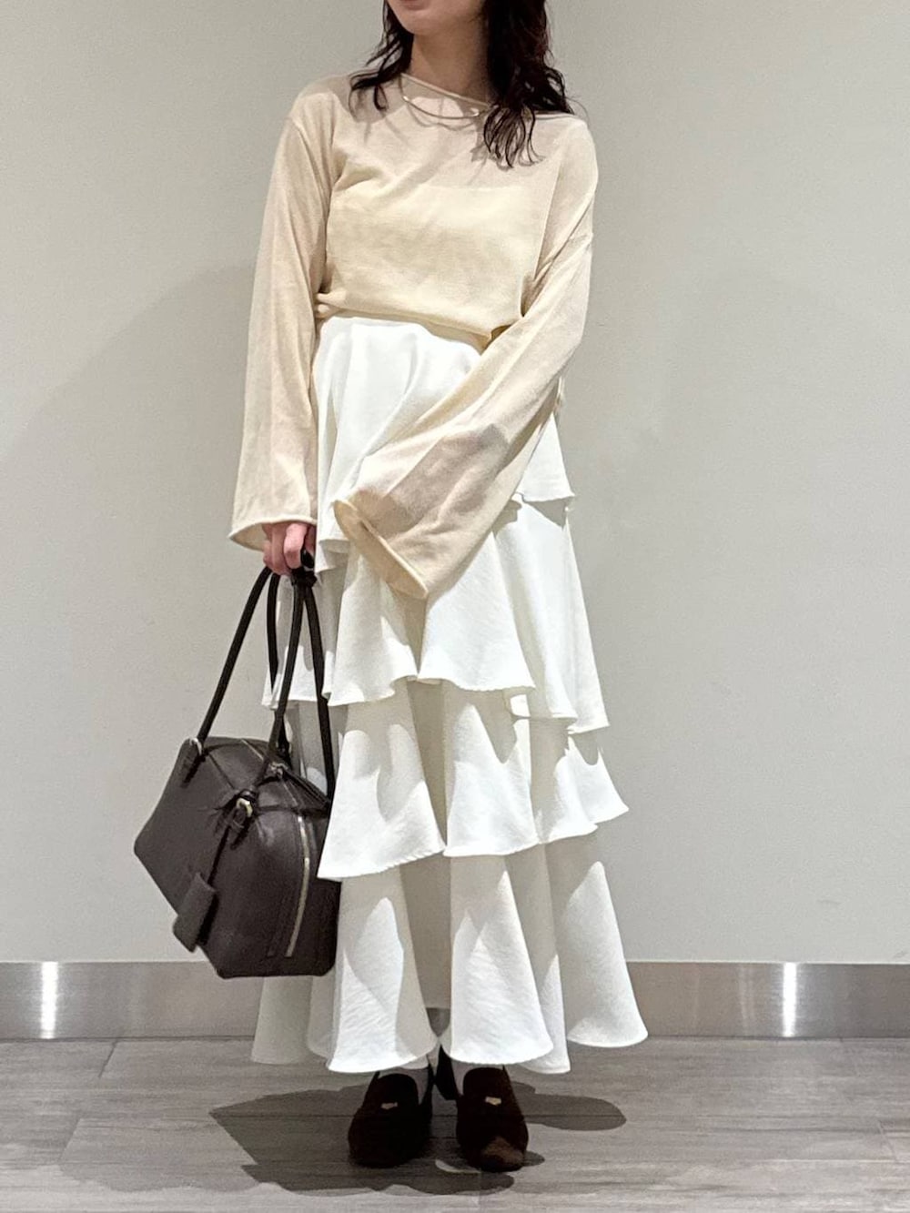 ホワイト系のニット/セーター、ブラウン系のハンドバッグ、ブラウン系のローファーを着用したレディースの春コーディネートの6枚目の写真