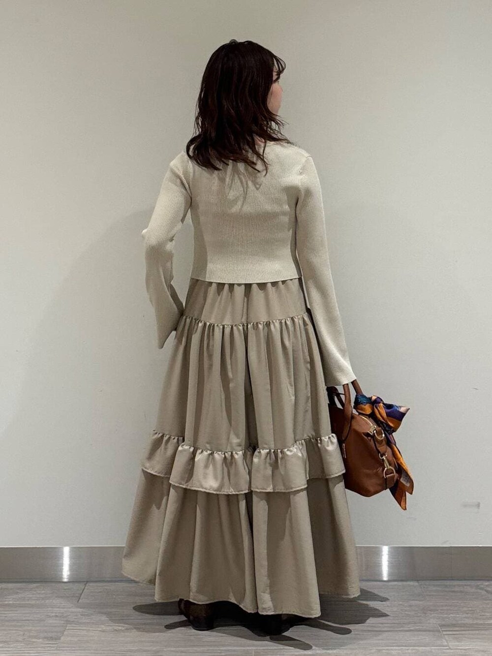 ブラウン系のボストンバッグ、ホワイト系のキャミソール、ブラウン系のローファーを着用したレディースの冬コーディネートの3枚目の写真