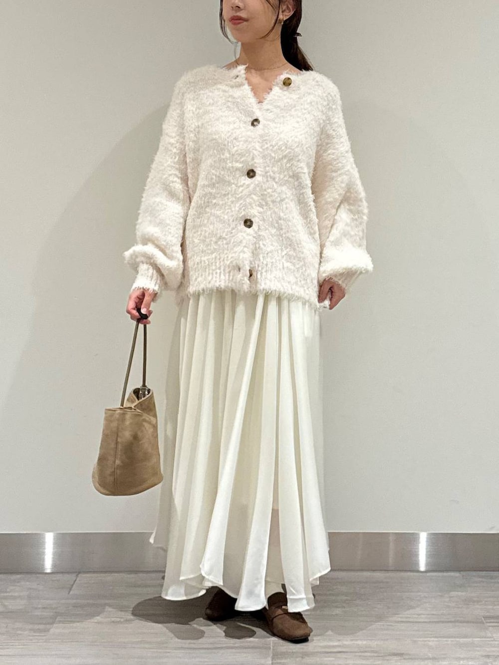 ホワイト系のカーディガン/ボレロ、ホワイト系のスカート、ブラウン系のローファーを着用したレディースの秋コーディネートの5枚目の写真