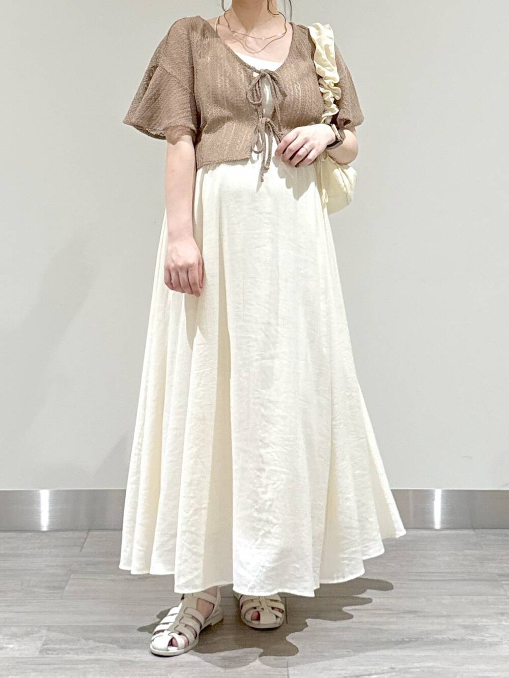 ホワイト系のショルダーバッグ、ブラウン系のカーディガン/ボレロ、ホワイト系のワンピースを着用したレディースの夏コーディネートの5枚目の写真