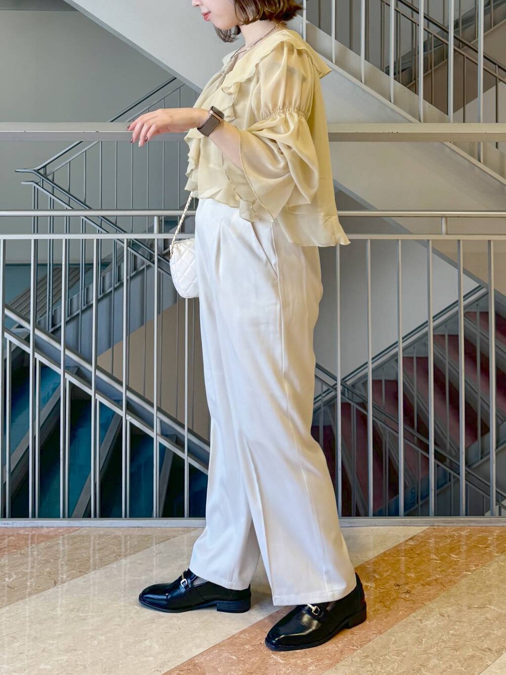 ブラック系のローファー、イエロー系のシャツ/ブラウス、ホワイト系のショルダーバッグを着用したレディースの冬コーディネートの3枚目の写真