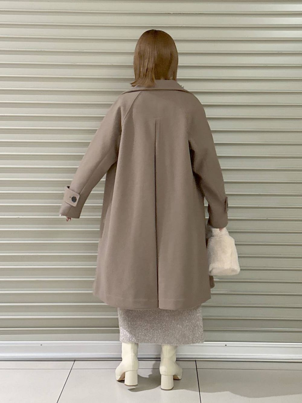 ブラウン系のチェスターコート、ホワイト系のブーツ、ホワイト系のハンドバッグを着用したレディースの冬コーディネートの4枚目の写真