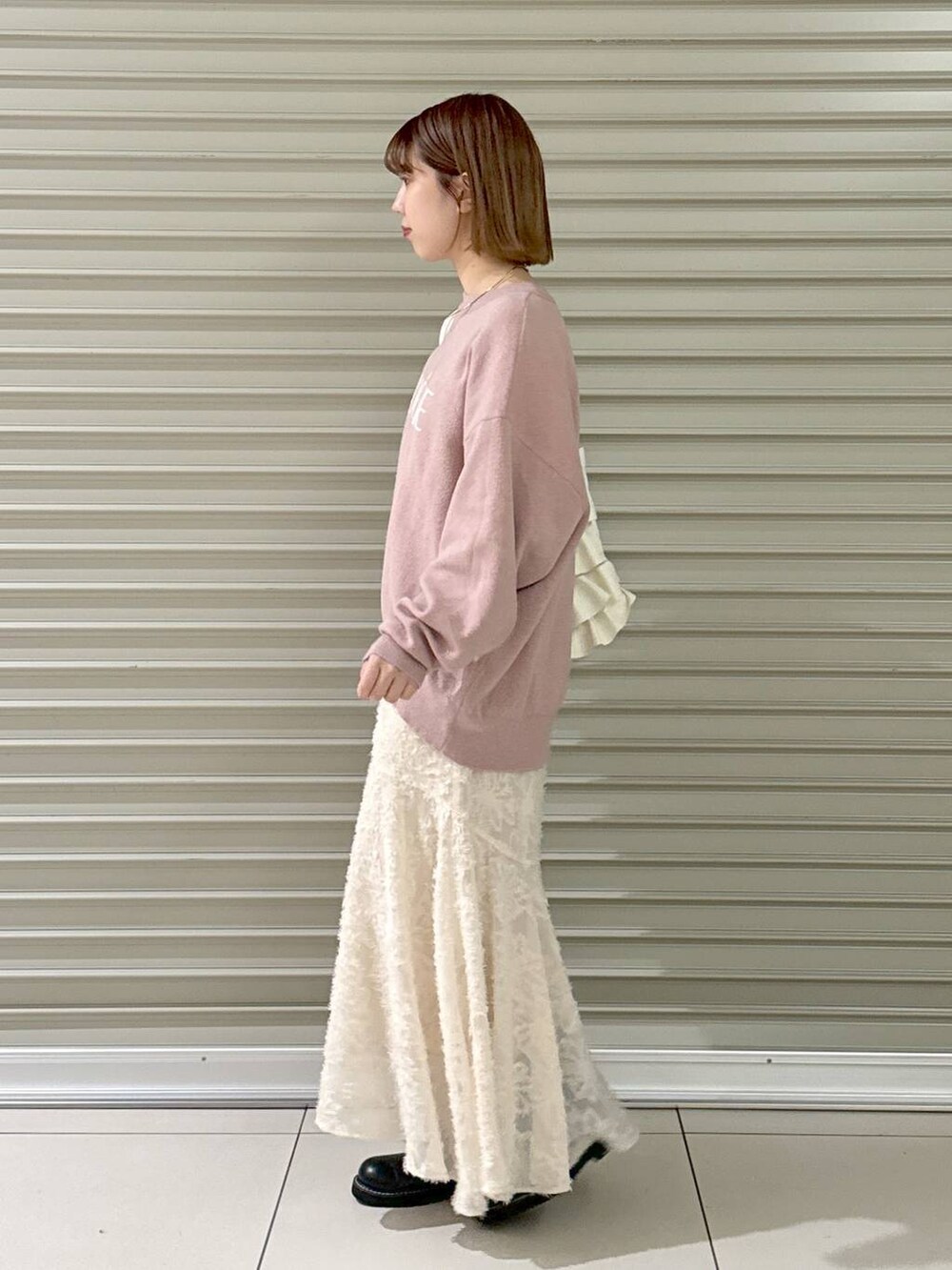 ブラック系のブーツ、ピンク系のニット/セーター、ホワイト系のトートバッグを着用したレディースの冬コーディネートの3枚目の写真