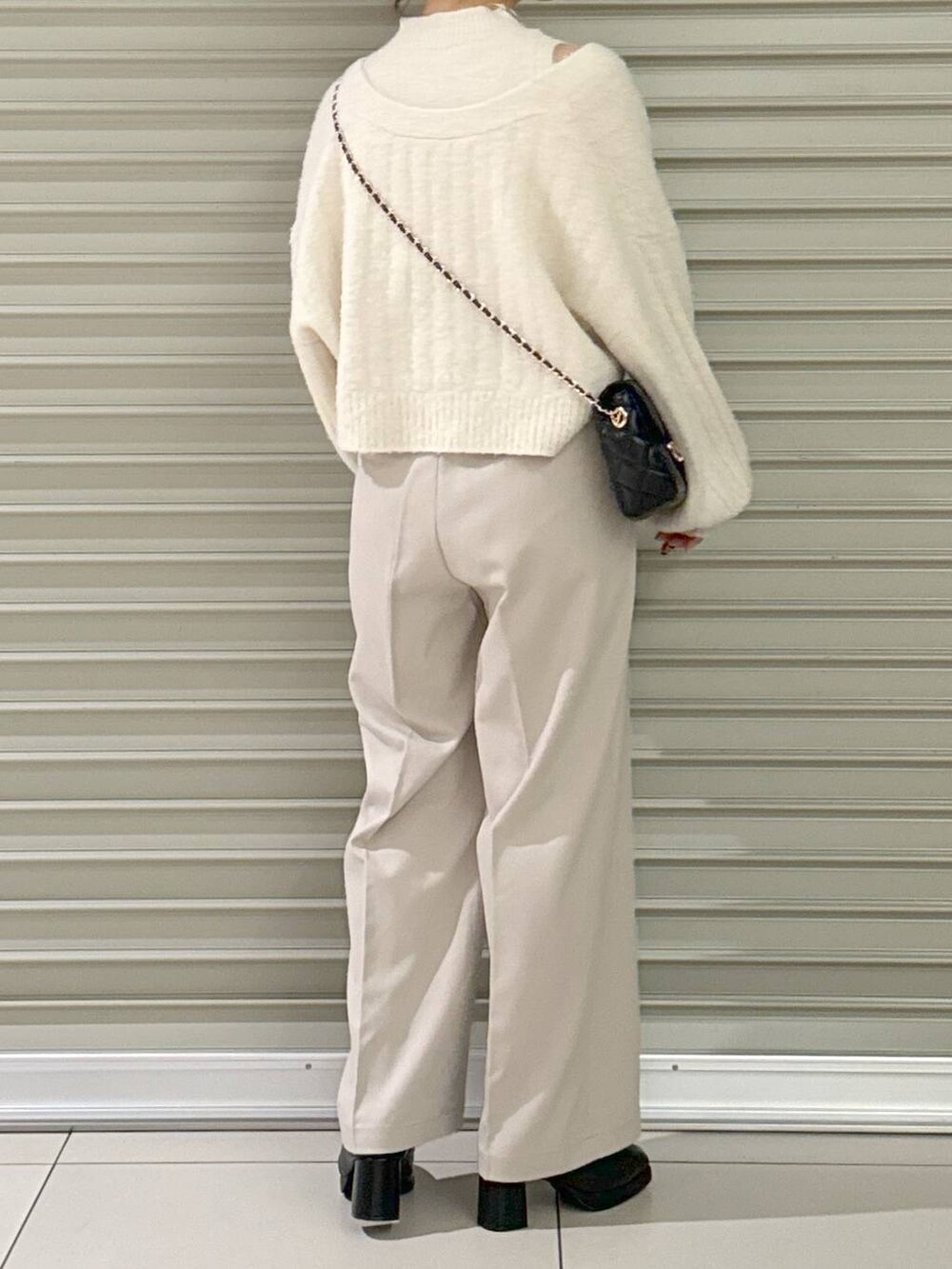 ブラック系のショルダーバッグ、ブラック系のブーツ、ホワイト系のその他パンツを着用したレディースの秋コーディネートの4枚目の写真