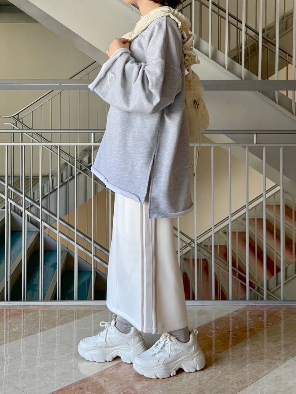 ホワイト系のスカート、グレー系のスウェット、ホワイト系のハンドバッグを着用したレディースの冬コーディネートの5枚目の写真