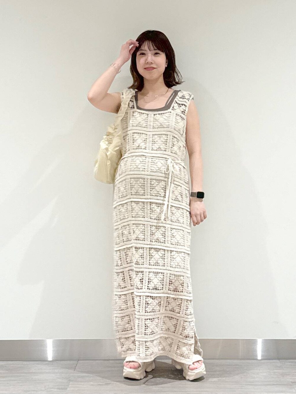 ホワイト系のワンピース、ブラウン系のニット/セーター、ホワイト系のサンダルを着用したレディースの春コーディネートの4枚目の写真