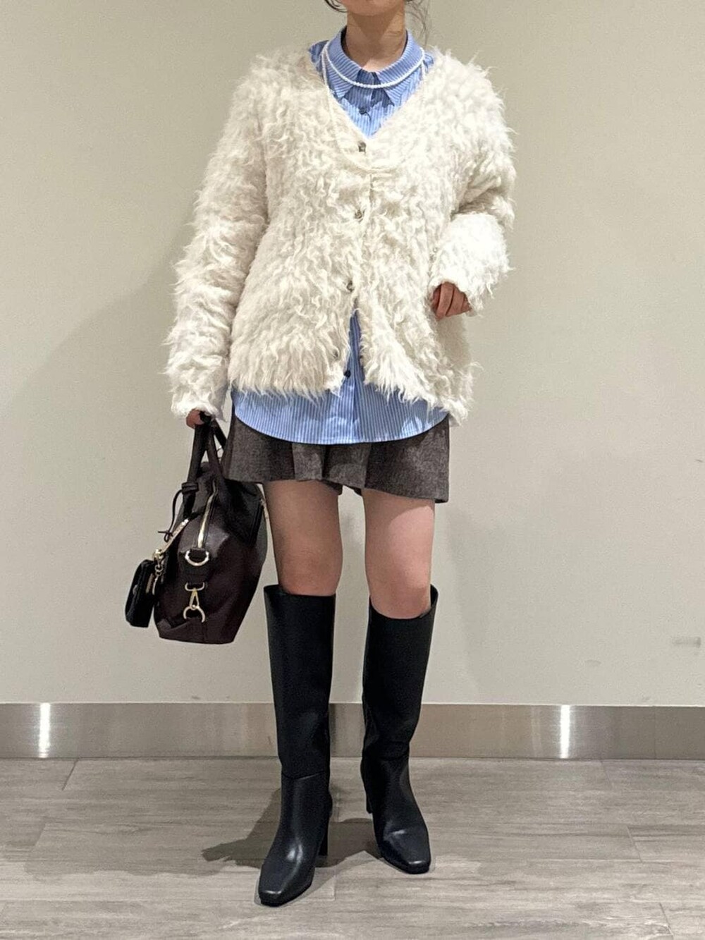 ブラウン系のボストンバッグ、ホワイト系のカーディガン/ボレロ、ブラウン系のその他パンツを着用したレディースの冬コーディネートの5枚目の写真