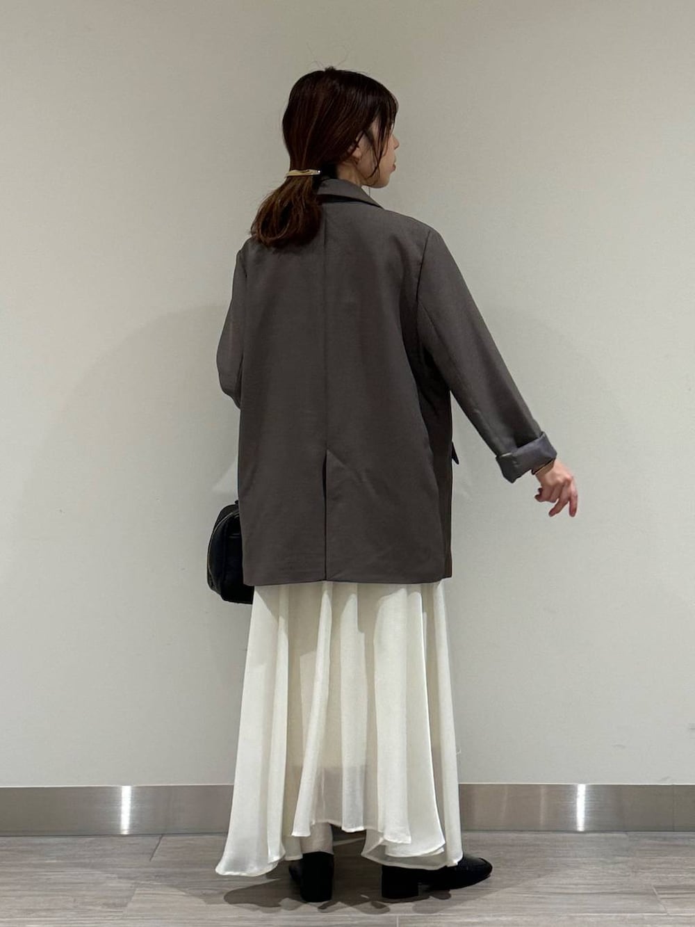 ブラック系のハンドバッグ、ベージュ系のテーラードジャケット、ホワイト系のスカートを着用したレディースの秋コーディネートの2枚目の写真