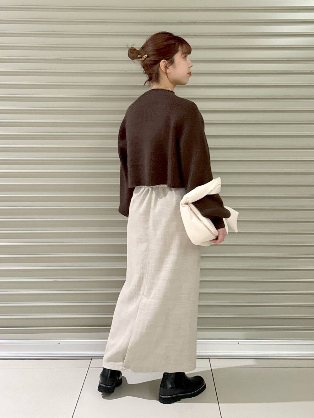 ブラック系のブーツ、ホワイト系のハンドバッグ、ホワイト系のスカートを着用したレディースの冬コーディネートの3枚目の写真