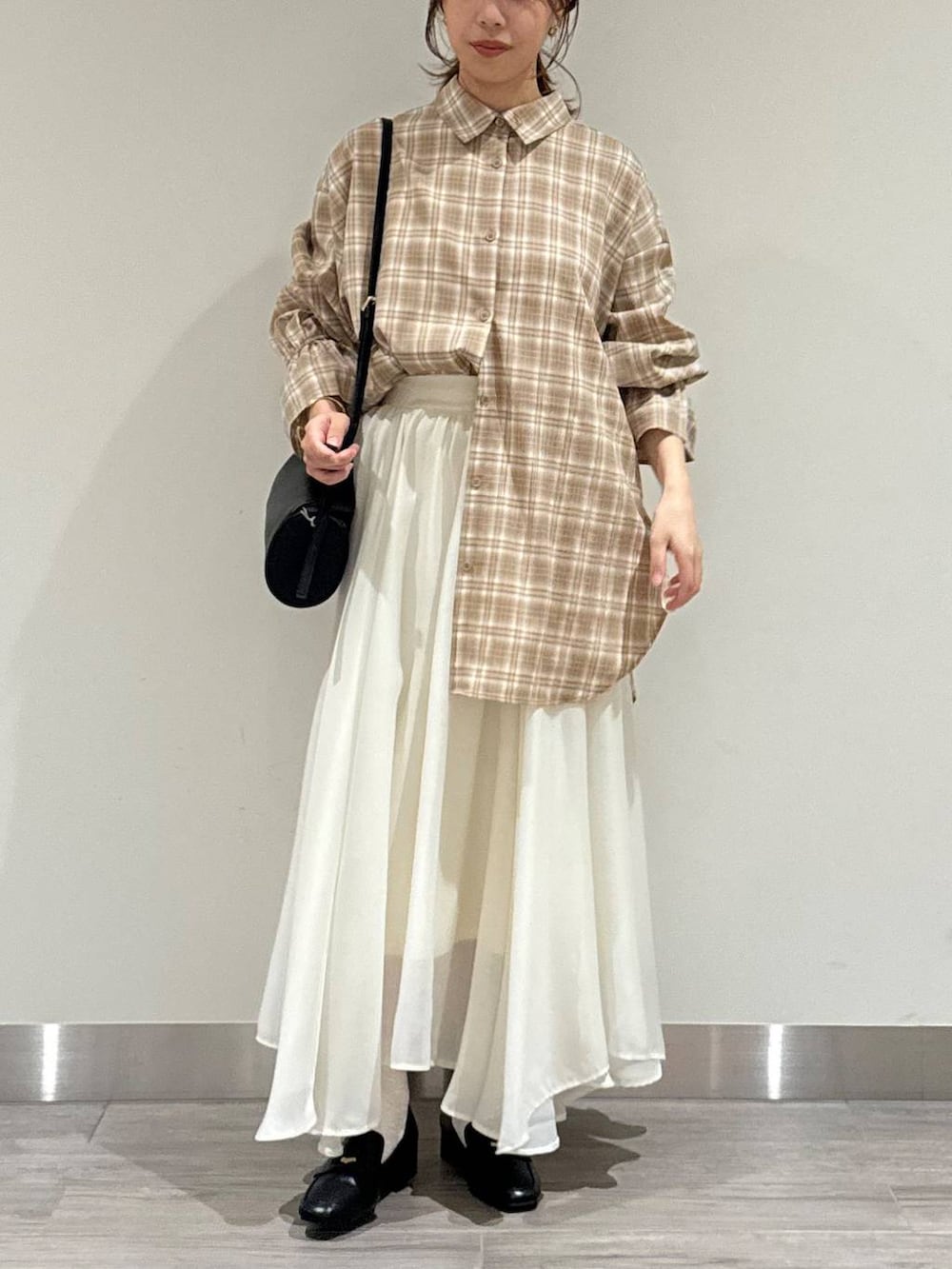 ベージュ系のシャツ/ブラウス、ブラック系のショルダーバッグ、ホワイト系のスカートを着用したレディースの秋コーディネートの2枚目の写真