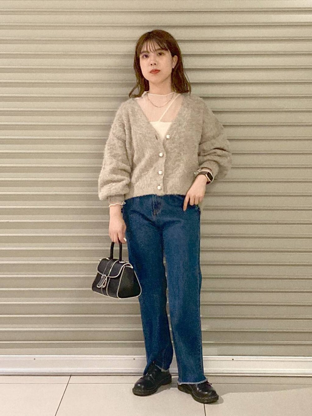 ブルー系のデニムパンツ、ブラック系のハンドバッグ、ブラウン系のカーディガン/ボレロを着用したレディースの秋コーディネートの4枚目の写真