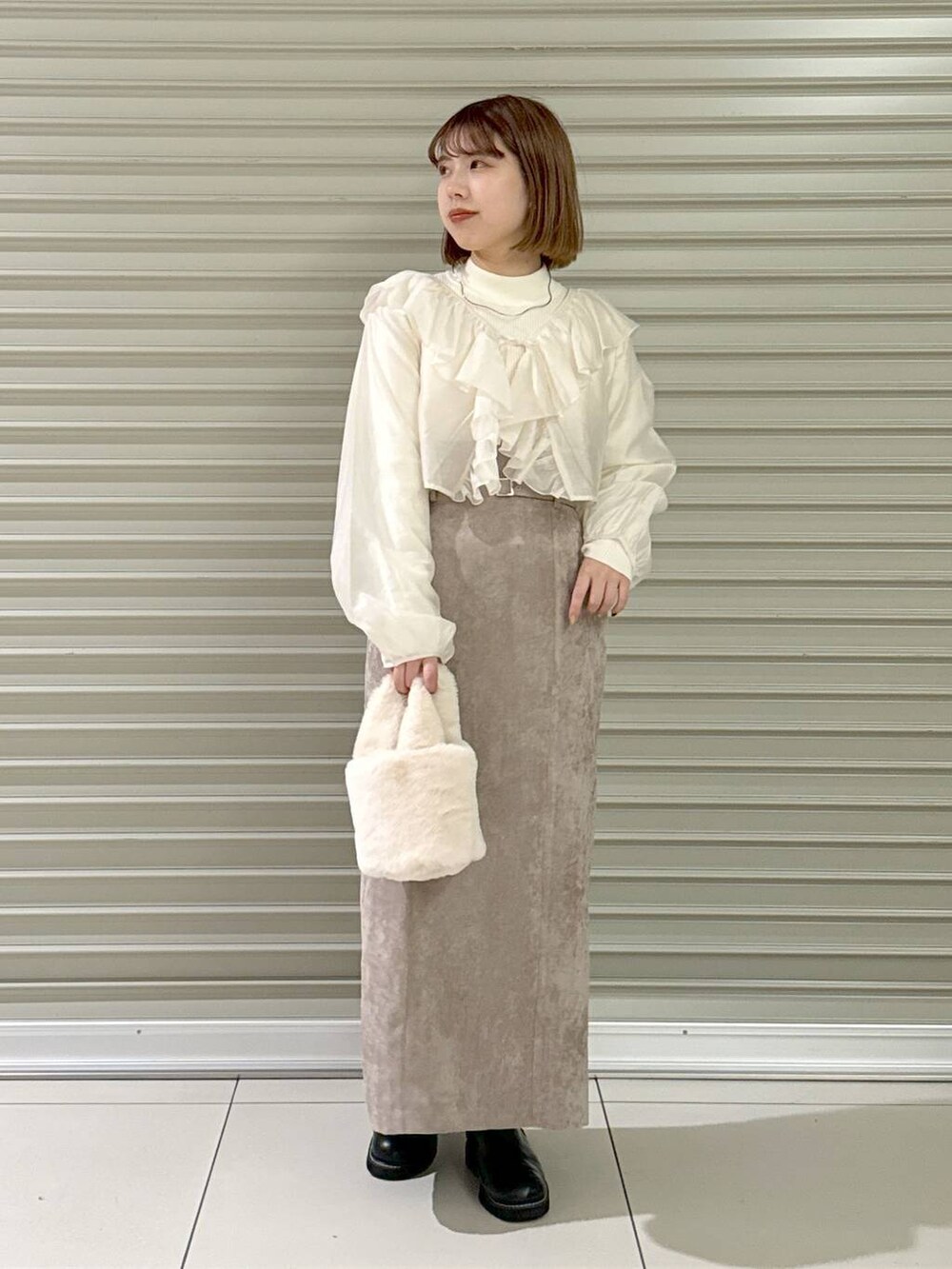 ブラウン系のスカート、ブラック系のブーツ、ホワイト系のハンドバッグを着用したレディースの冬コーディネートの4枚目の写真