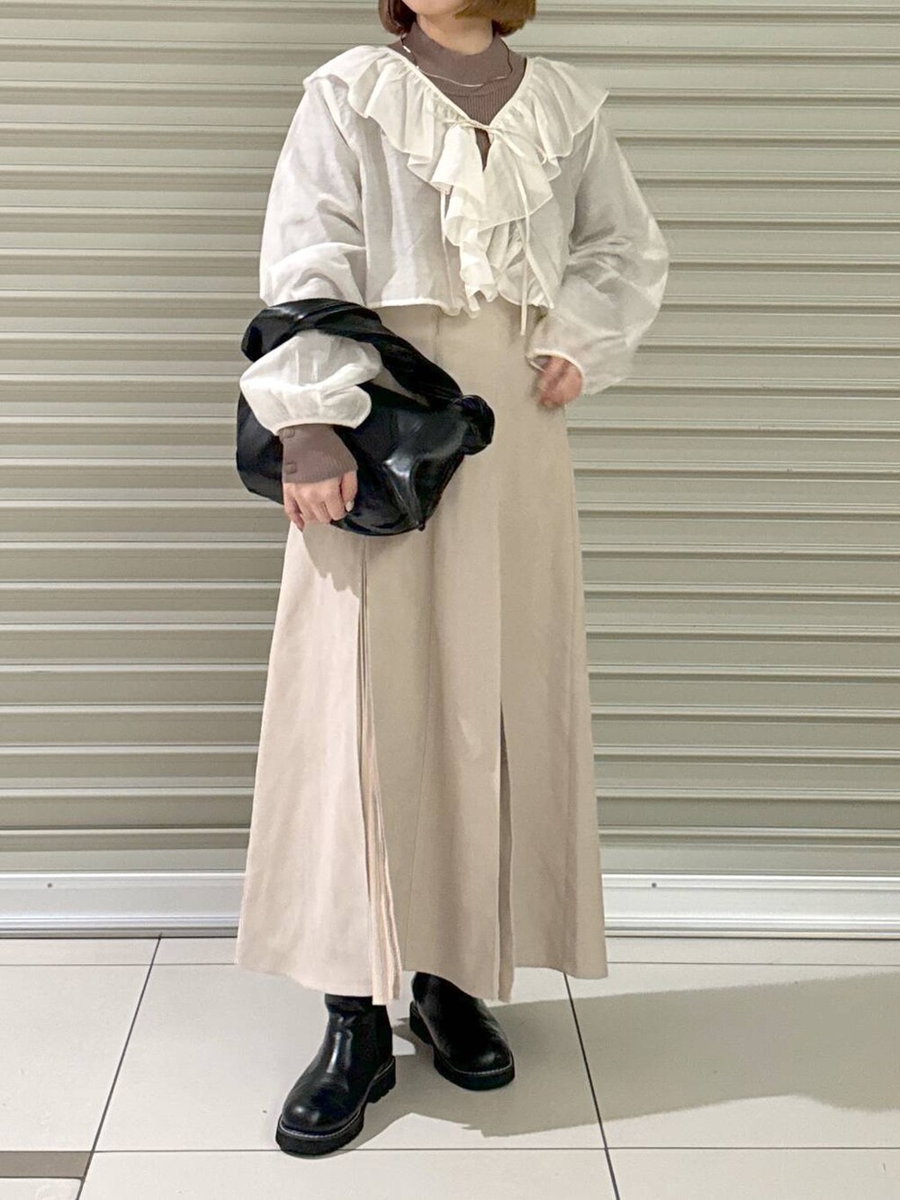 ブラック系のブーツ、ブラウン系のニット/セーター、ブラック系のハンドバッグを着用したレディースの冬コーディネートの4枚目の写真