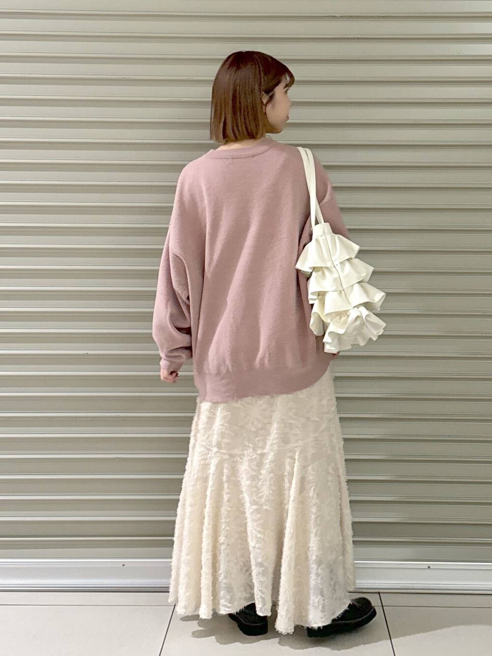 ブラック系のブーツ、ピンク系のニット/セーター、ホワイト系のトートバッグを着用したレディースの冬コーディネートの4枚目の写真