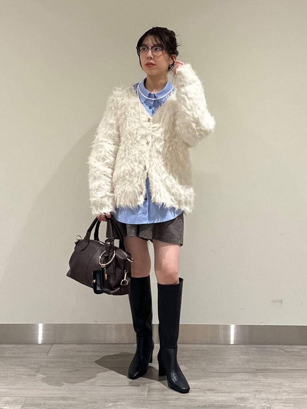 ブラウン系のボストンバッグ、ホワイト系のカーディガン/ボレロ、ブラウン系のその他パンツを着用したレディースの冬コーディネートの6枚目の写真