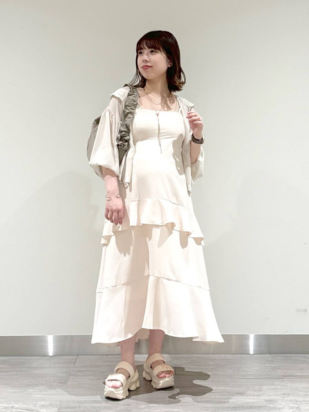 ブラウン系のショルダーバッグ、ベージュ系のキャミソール、ホワイト系のパーカーを着用したレディースの夏コーディネートの4枚目の写真